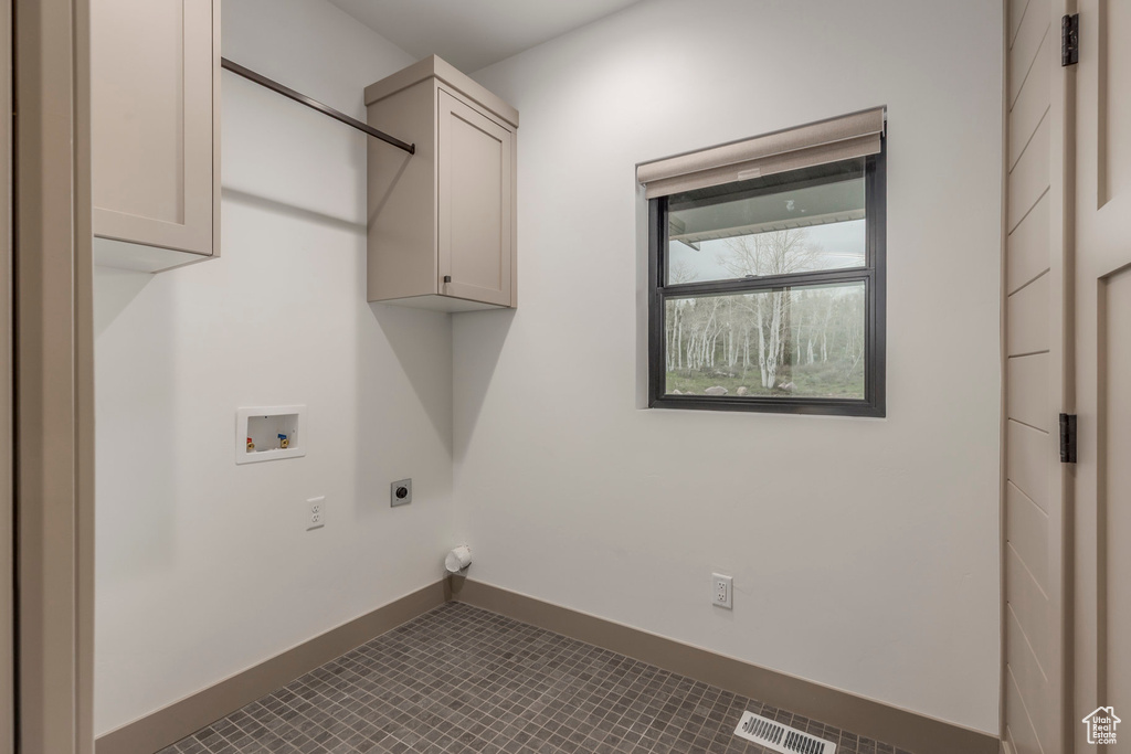 Laundry room with electric dryer hookup, washer hookup, cabinet space, baseboards, and tile patterned flooring