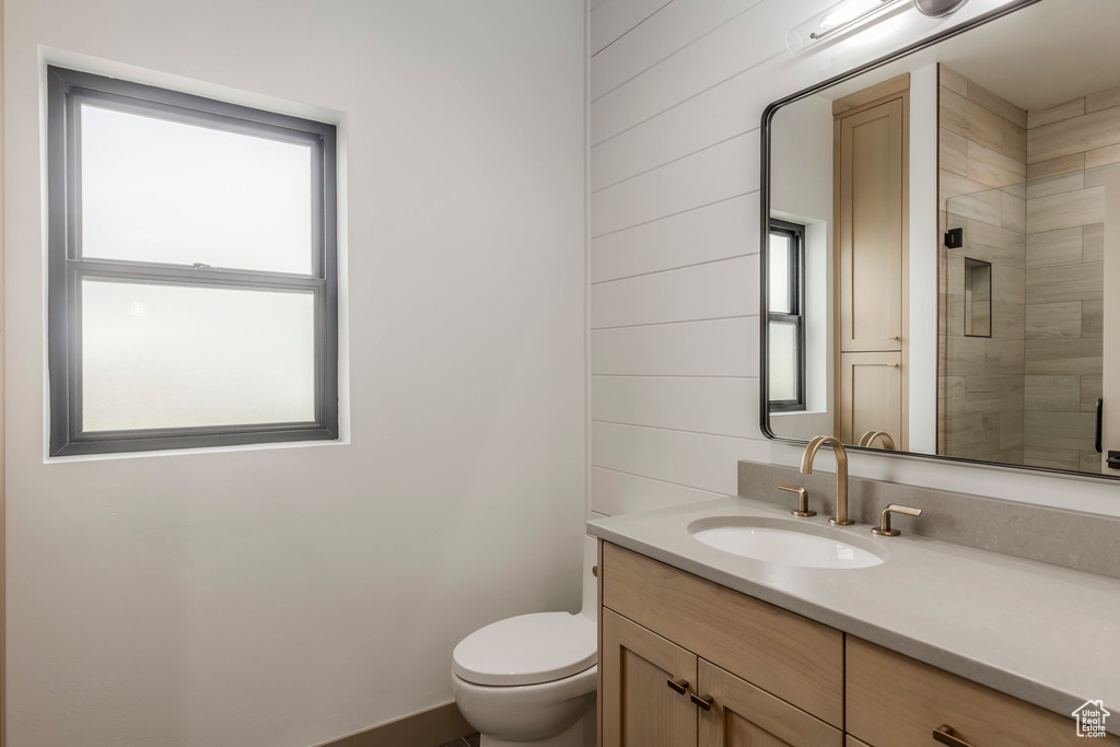 Bathroom featuring vanity, toilet, and a tile shower