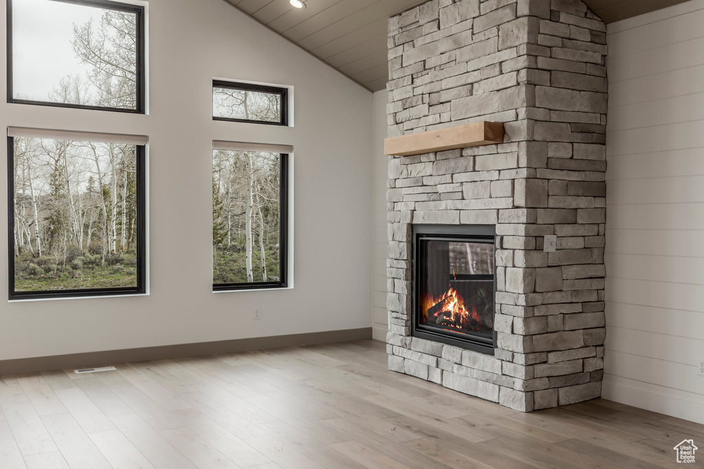 Unfurnished living room with a fireplace, high vaulted ceiling, wood finished floors, and baseboards