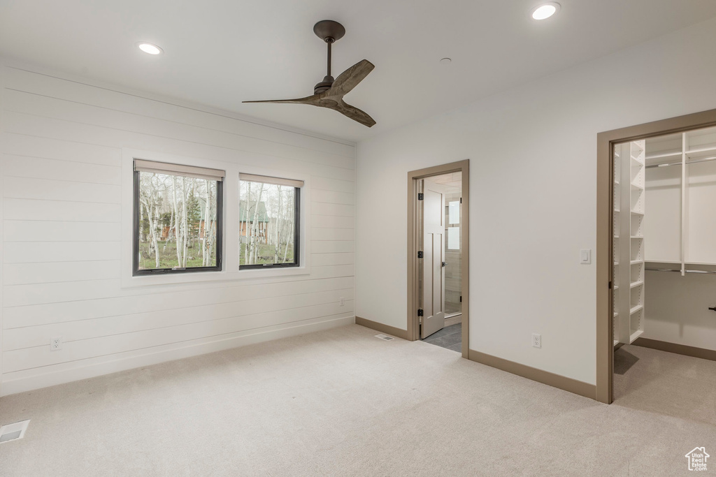Unfurnished bedroom featuring a spacious closet, light colored carpet, recessed lighting, a closet, and baseboards
