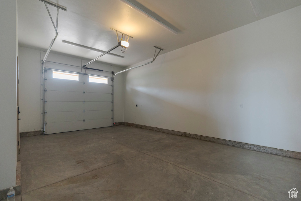 Garage featuring a garage door opener and baseboards