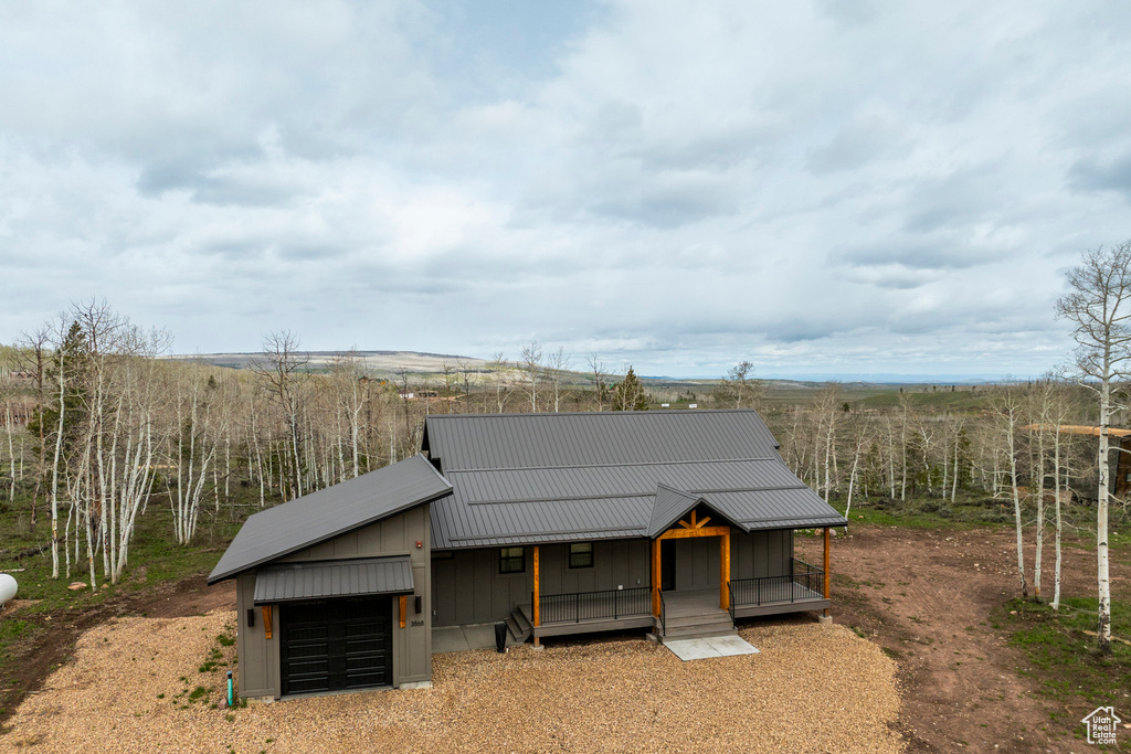 View of front of home with a garage, a porch, board and batten siding, and metal roof