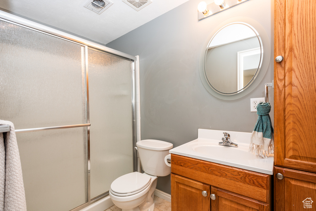 Full bathroom with a shower stall, toilet, vanity, and tile patterned floors