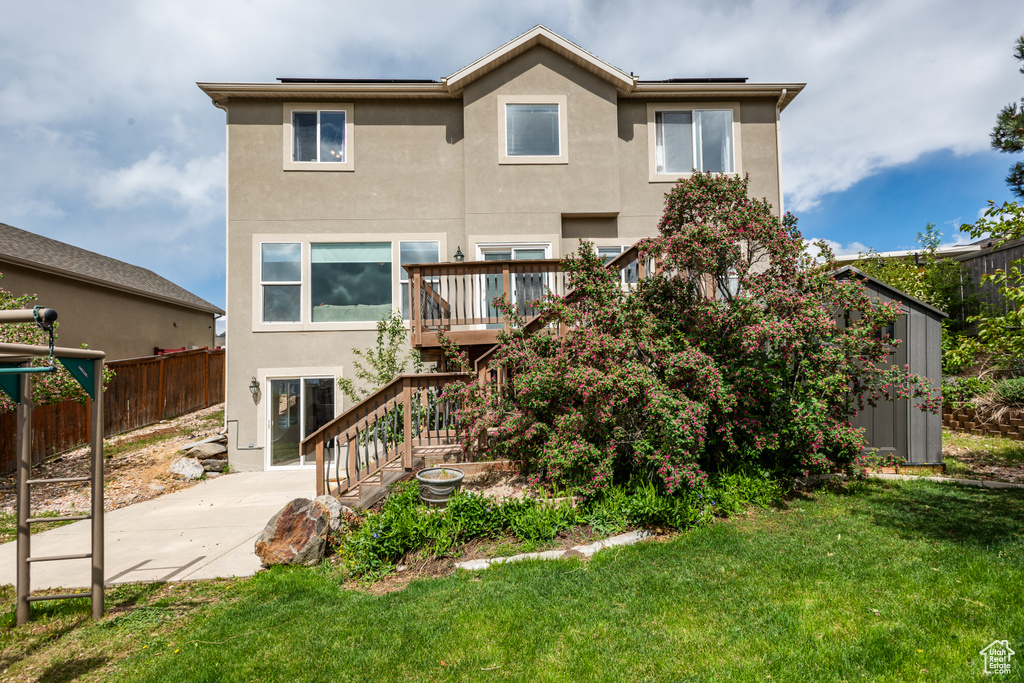 Rear view of house with stucco siding, a patio, stairway, and a deck