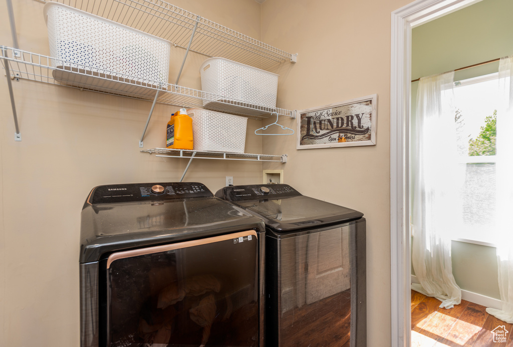 Clothes washing area featuring independent washer and dryer and wood finished floors