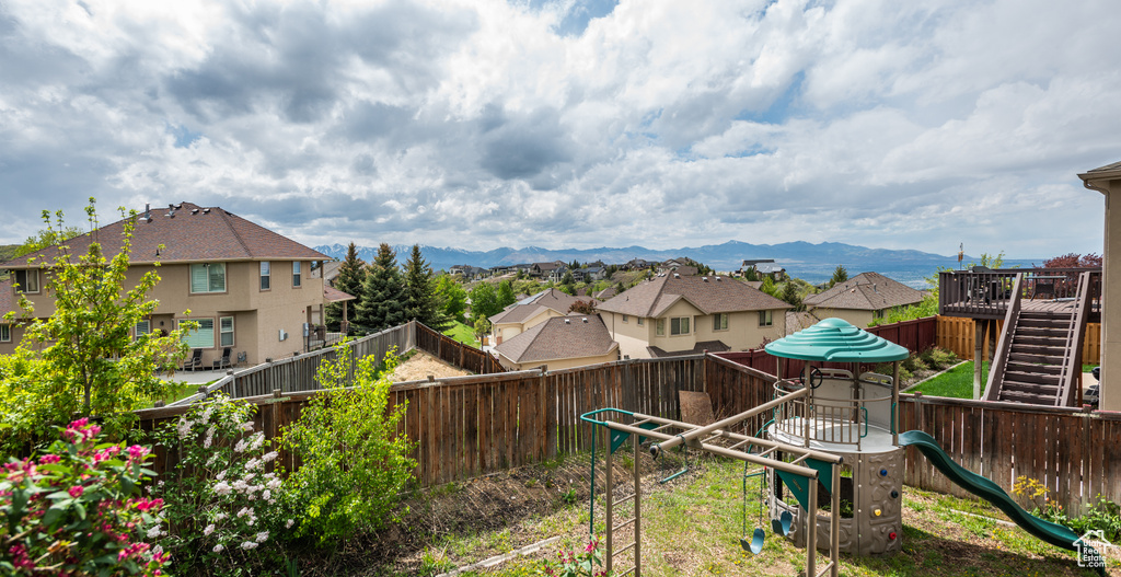 Fenced backyard featuring a playground, a residential view, and a mountain view