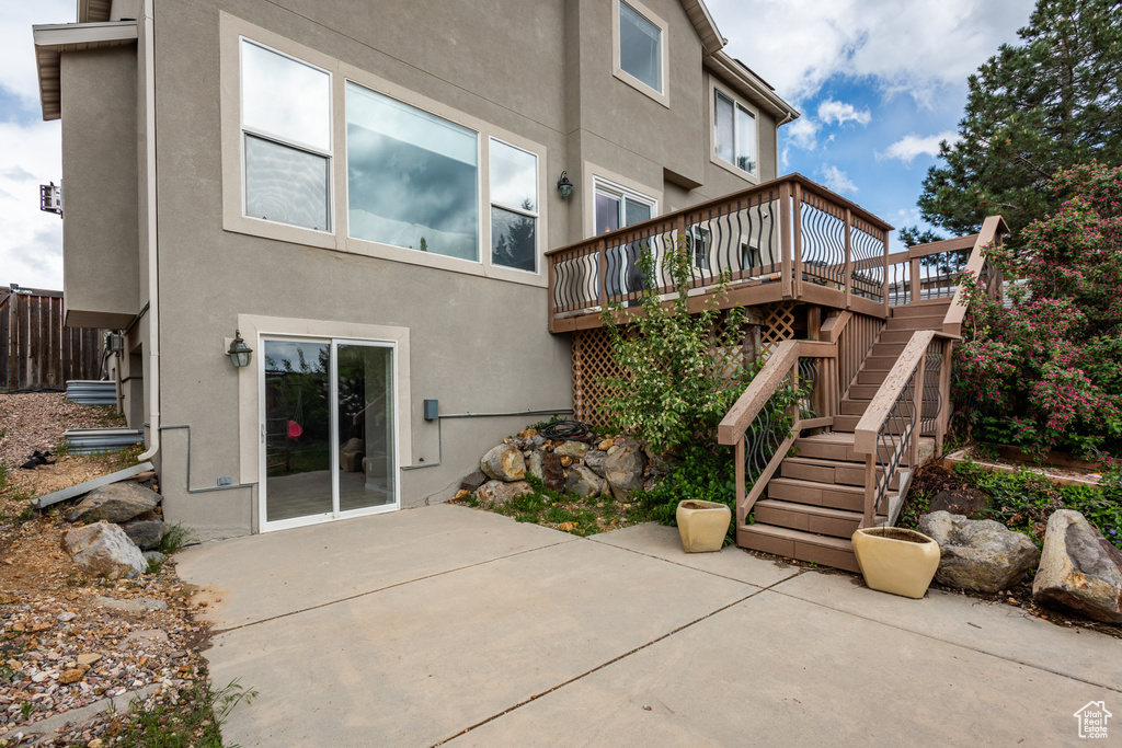 Back of property with stucco siding, a patio, a wooden deck, and stairs