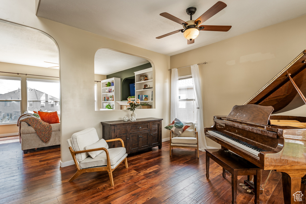 Sitting room with a ceiling fan, dark wood-style floors, baseboards, and arched walkways
