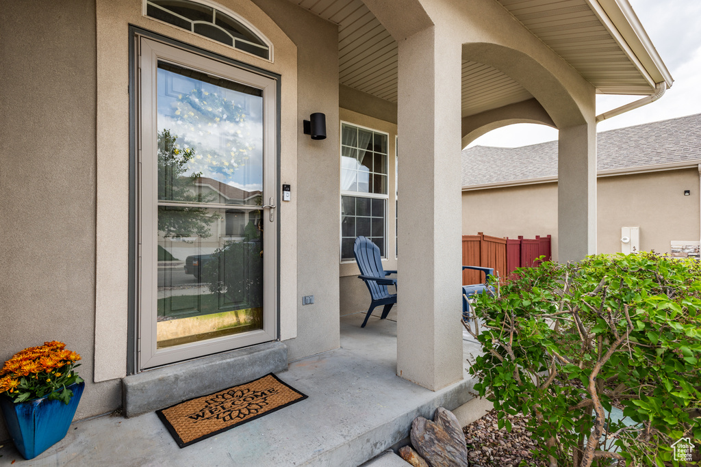Property entrance featuring stucco siding, a porch, and fence