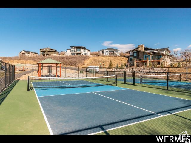 View of tennis court featuring fence and a gazebo