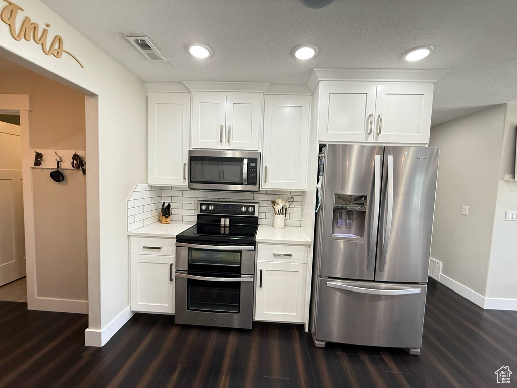 Kitchen with stainless steel appliances, baseboards, dark wood-style flooring, light countertops, and recessed lighting