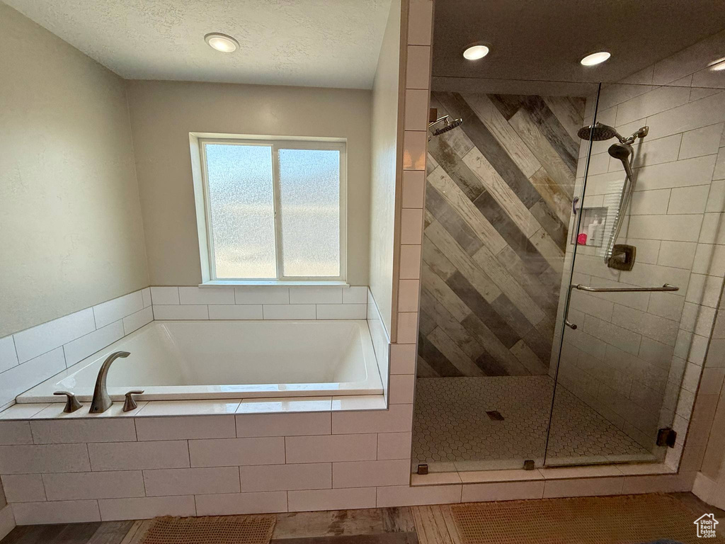 Full bathroom featuring a shower stall, a bath, recessed lighting, and a textured ceiling