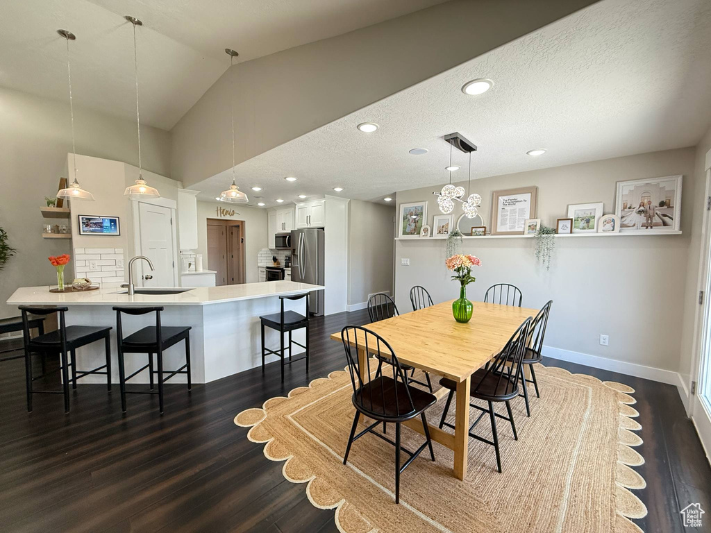 Dining room featuring baseboards, dark wood-style floors, vaulted ceiling, and recessed lighting