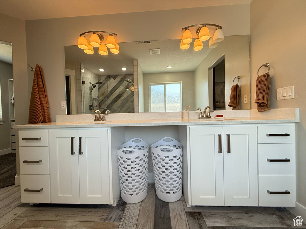 Full bath with a stall shower, a chandelier, vanity, and wood finished floors