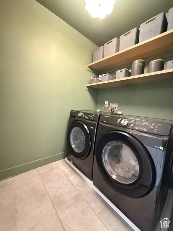 Laundry room featuring separate washer and dryer, light tile patterned flooring, and baseboards