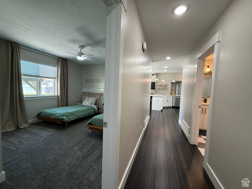 Hall featuring baseboards, dark wood-style floors, a textured ceiling, and recessed lighting