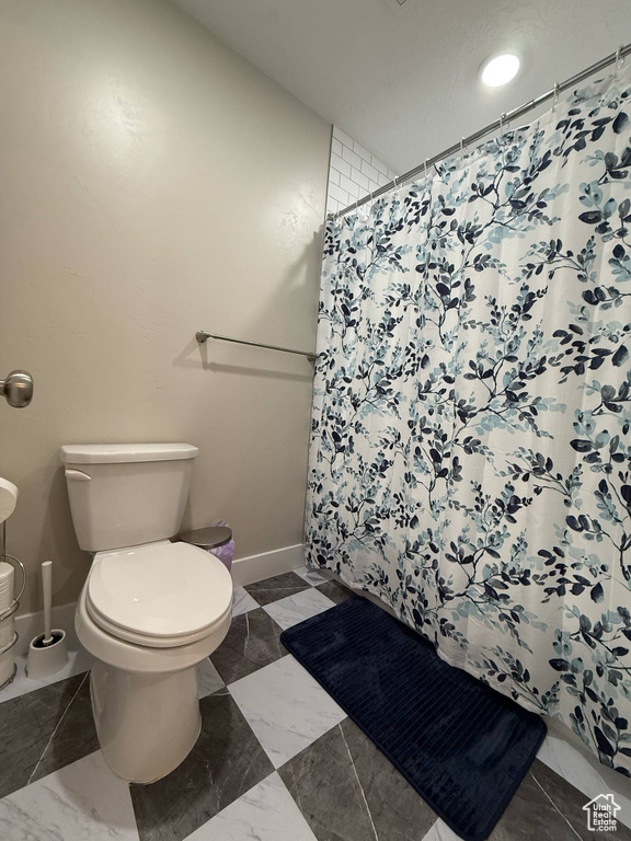Bathroom featuring toilet, baseboards, marble finish floors, and a shower with curtain
