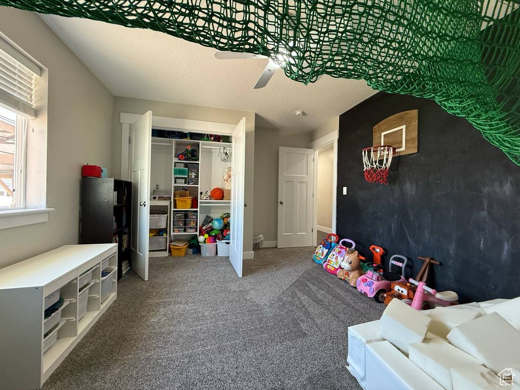 Playroom with a ceiling fan and carpet