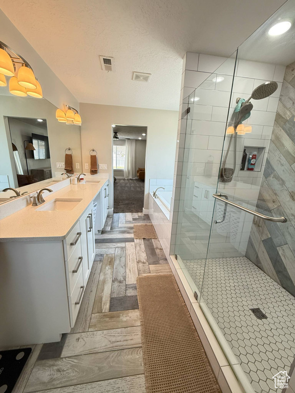Full bathroom with a stall shower, a bath, double vanity, and wood finished floors