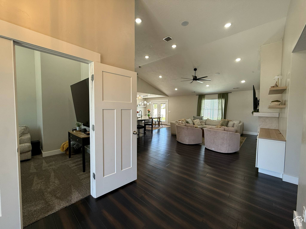 Living area with dark wood-type flooring, a ceiling fan, recessed lighting, lofted ceiling, and baseboards