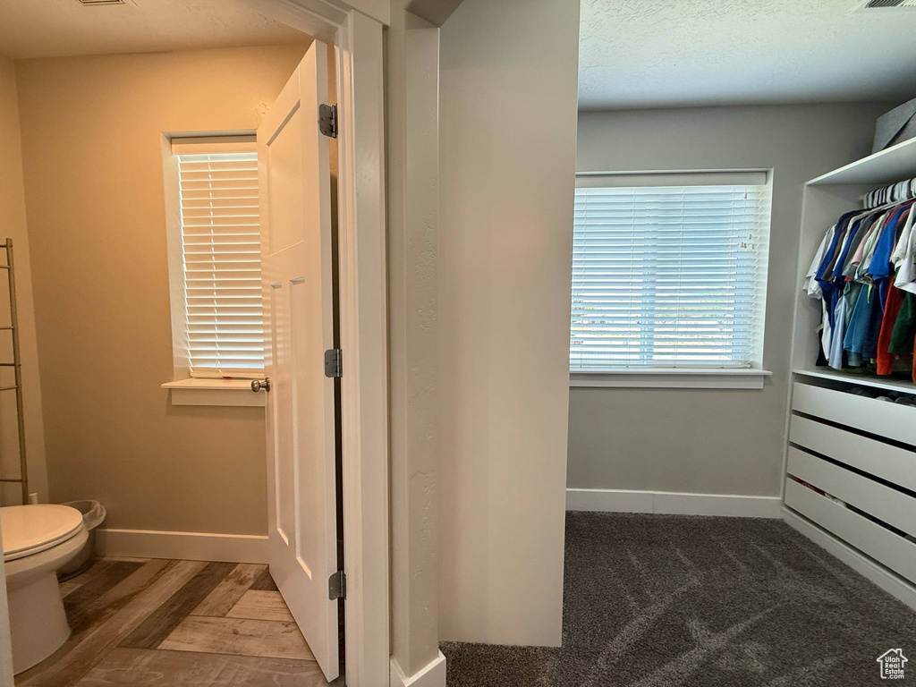 Bathroom featuring baseboards, toilet, and wood finished floors