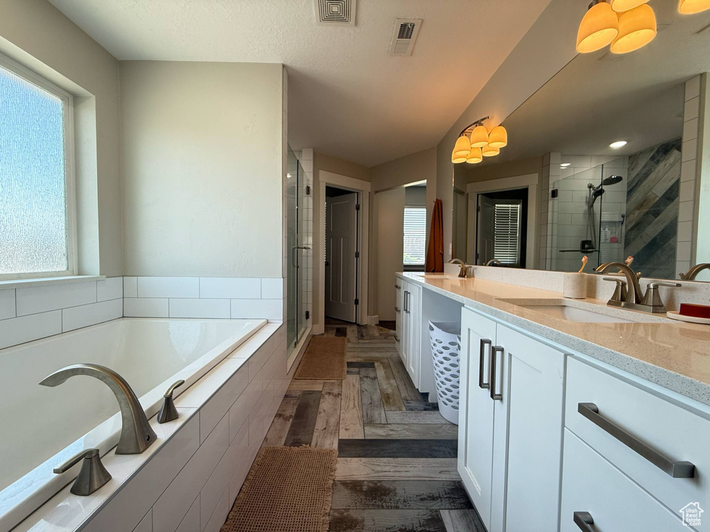 Full bathroom with a shower stall, a bath, double vanity, and plenty of natural light