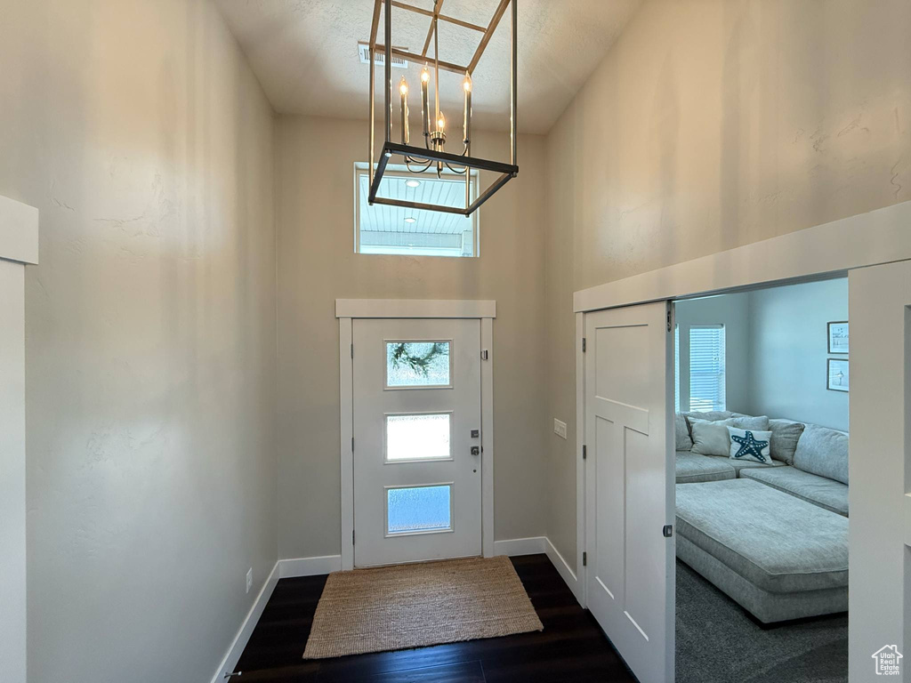 Entrance foyer with a chandelier, a high ceiling, dark wood-type flooring, and baseboards
