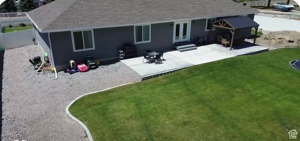 Rear view of property featuring french doors, a shingled roof, and a patio area
