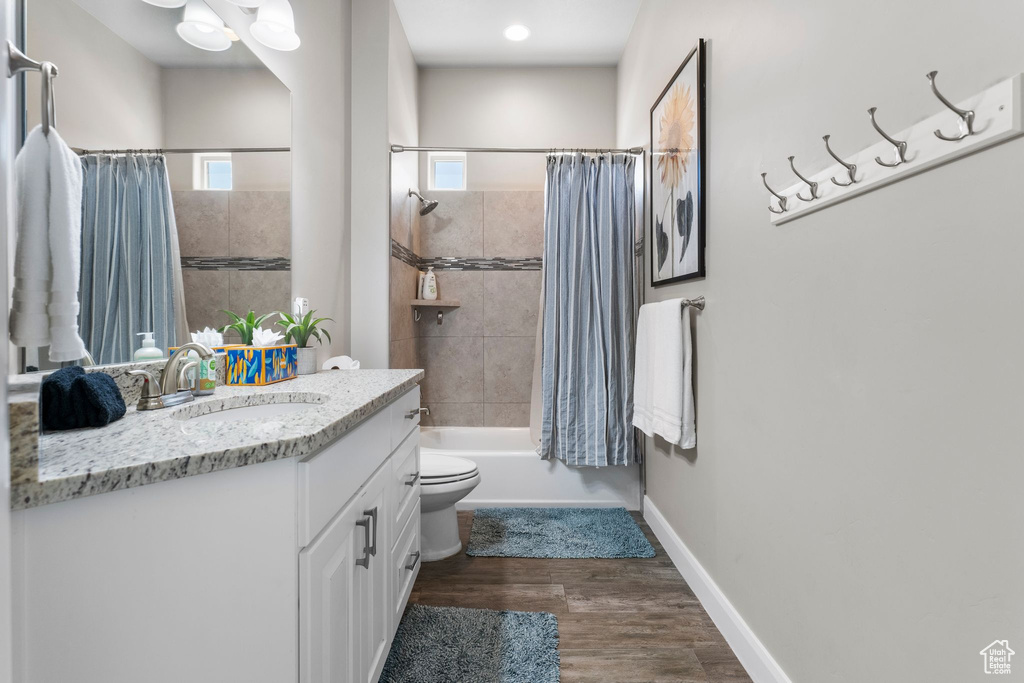 Bathroom featuring vanity, wood finished floors, shower / bathtub combination with curtain, and healthy amount of natural light