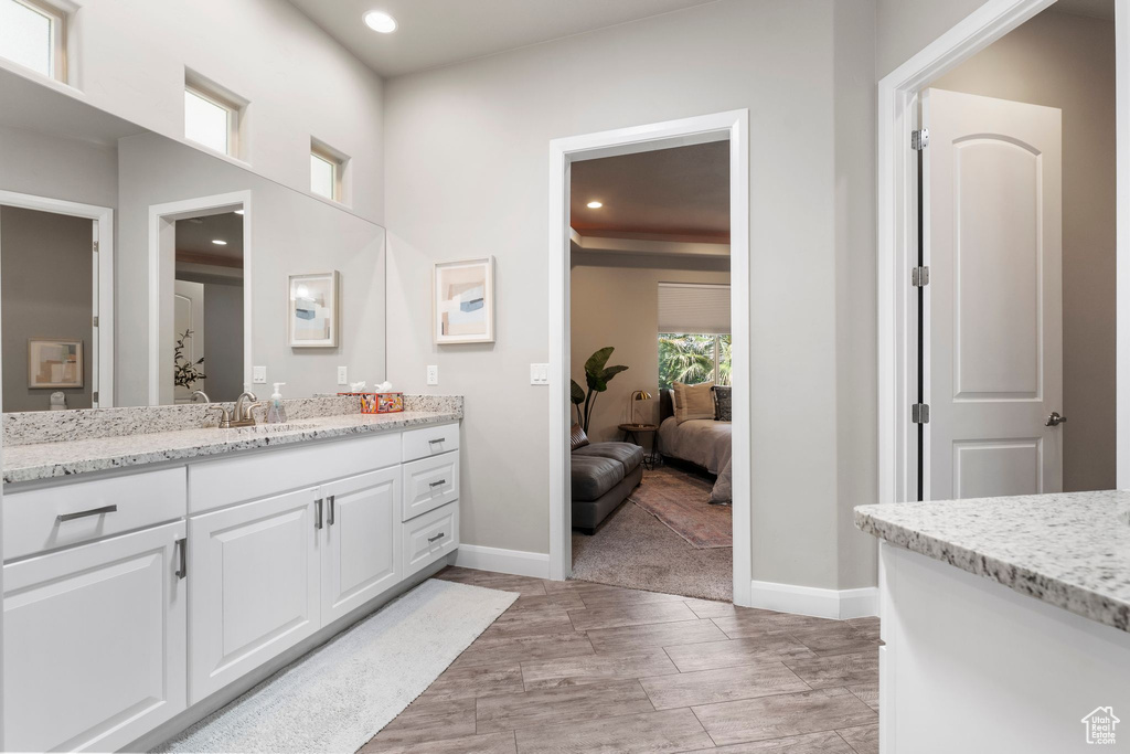 Bathroom featuring baseboards, recessed lighting, vanity, and ensuite bath