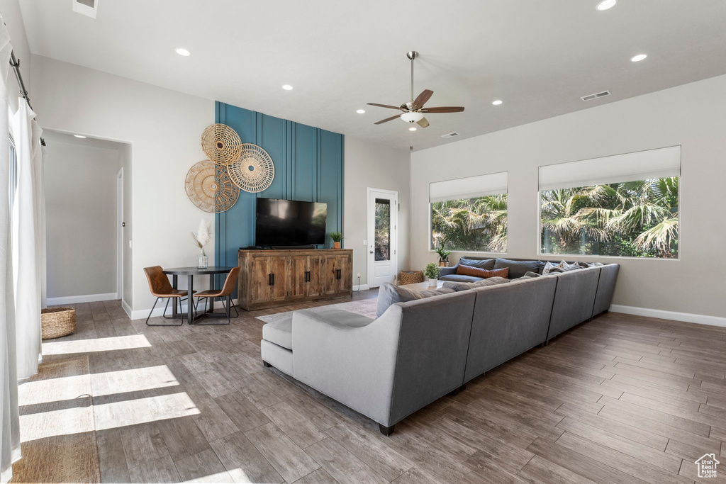 Living area with recessed lighting, healthy amount of natural light, ceiling fan, wood finished floors, and baseboards