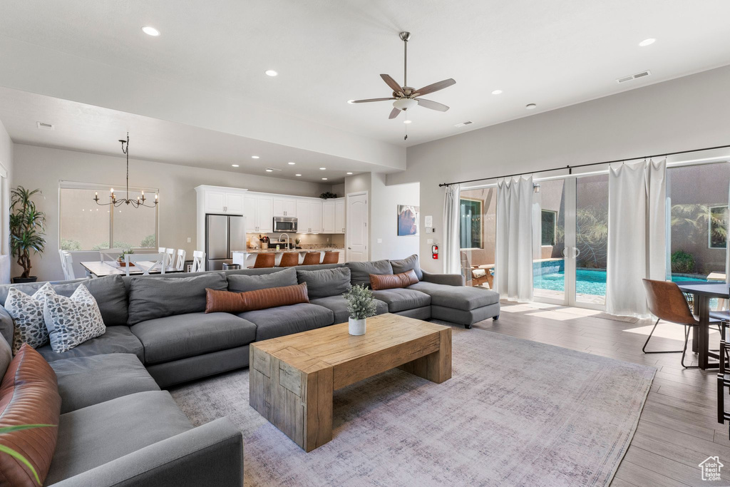 Living room with ceiling fan, recessed lighting, light wood-style flooring, and a chandelier
