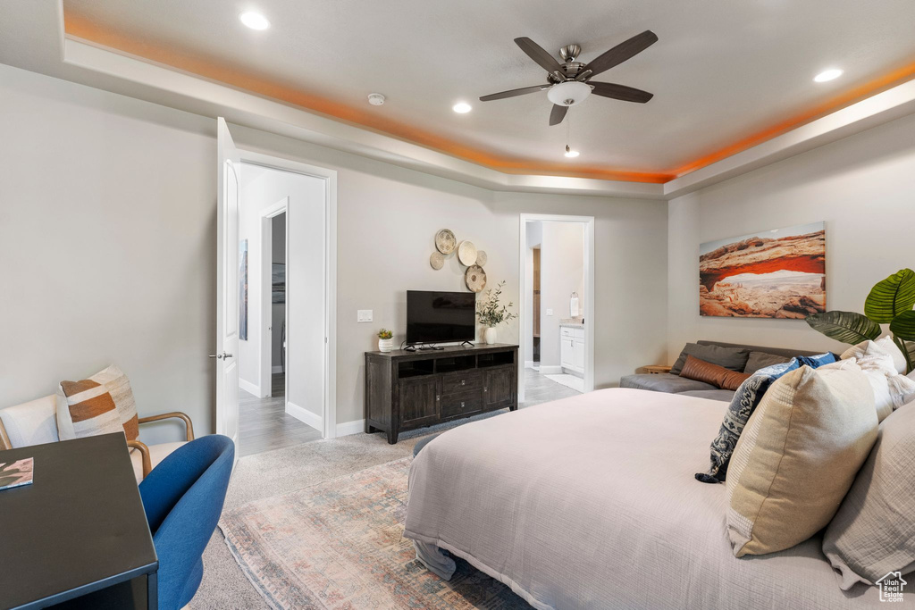 Bedroom featuring a raised ceiling, recessed lighting, baseboards, ensuite bathroom, and a ceiling fan