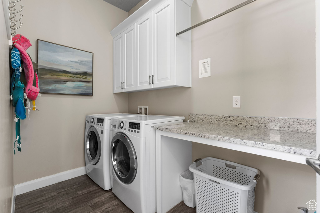 Clothes washing area with washer and dryer, cabinet space, dark wood-style floors, and baseboards