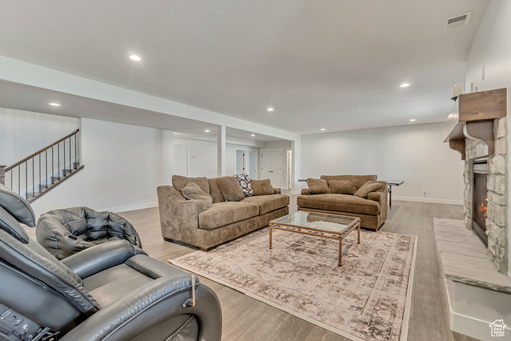 Living area with light wood-style flooring, stairs, baseboards, recessed lighting, and a fireplace