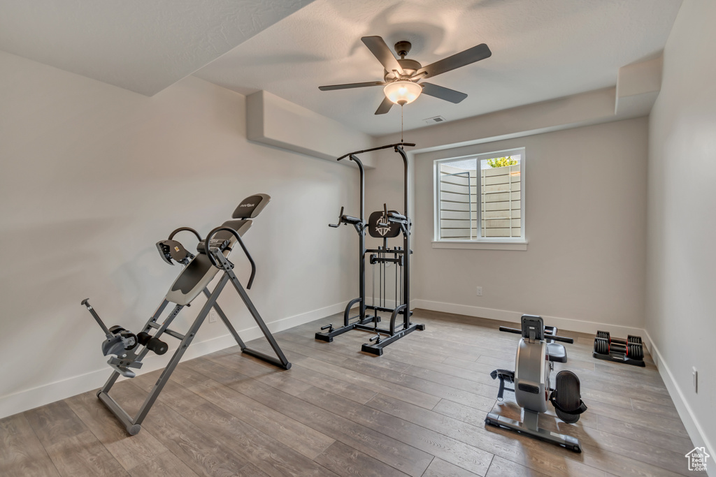 Exercise area with wood finished floors, baseboards, and ceiling fan