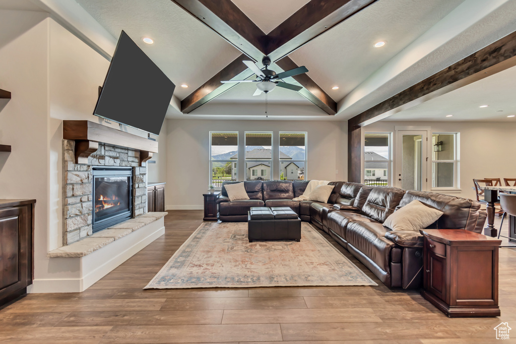 Living area with ceiling fan, wood finished floors, beamed ceiling, a fireplace, and recessed lighting