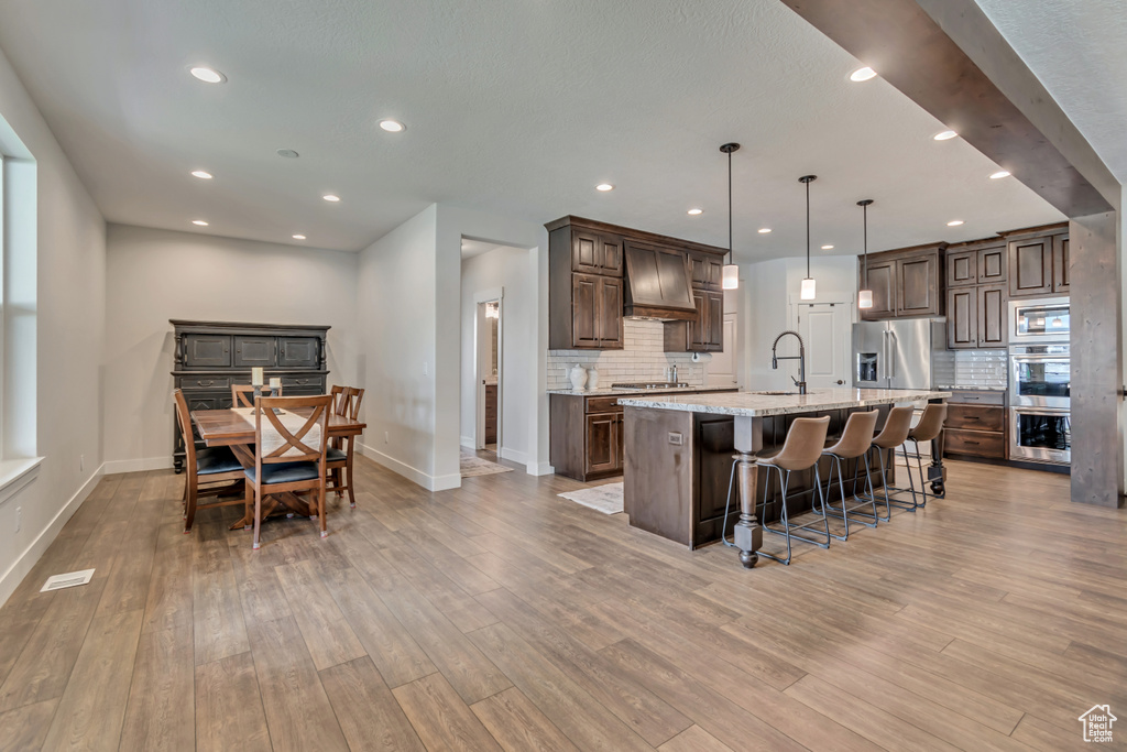 Kitchen with baseboards, light wood finished floors, a breakfast bar, and recessed lighting