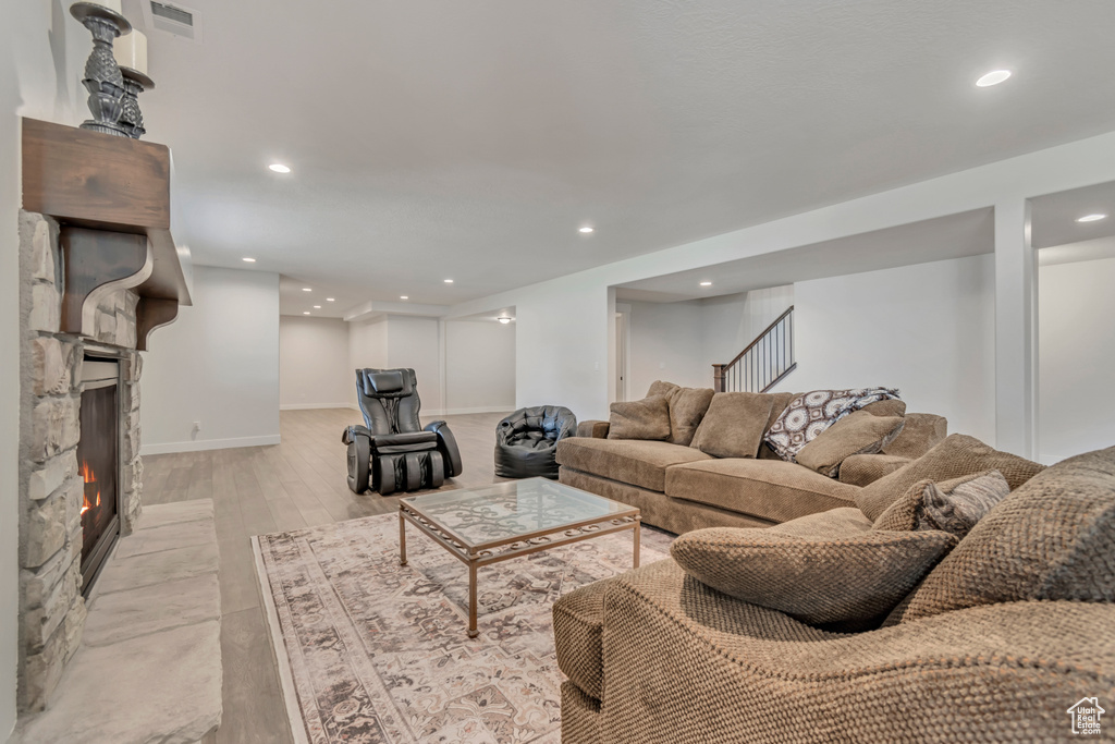 Living room featuring recessed lighting, stairway, baseboards, light wood-style flooring, and a fireplace