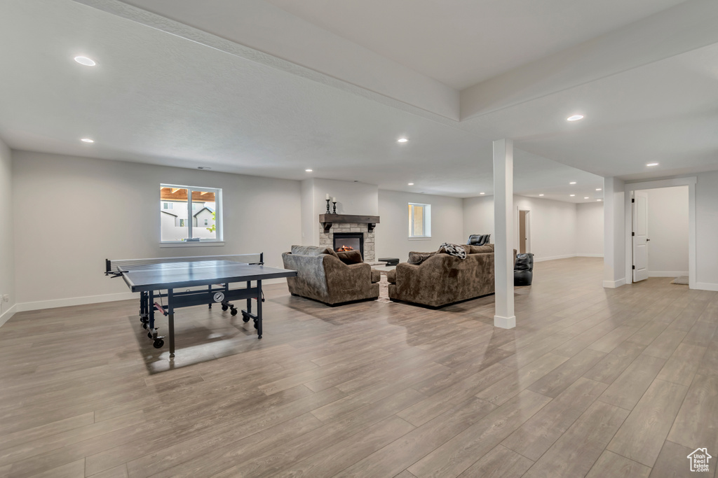 Rec room featuring light wood-style floors, recessed lighting, baseboards, and a stone fireplace