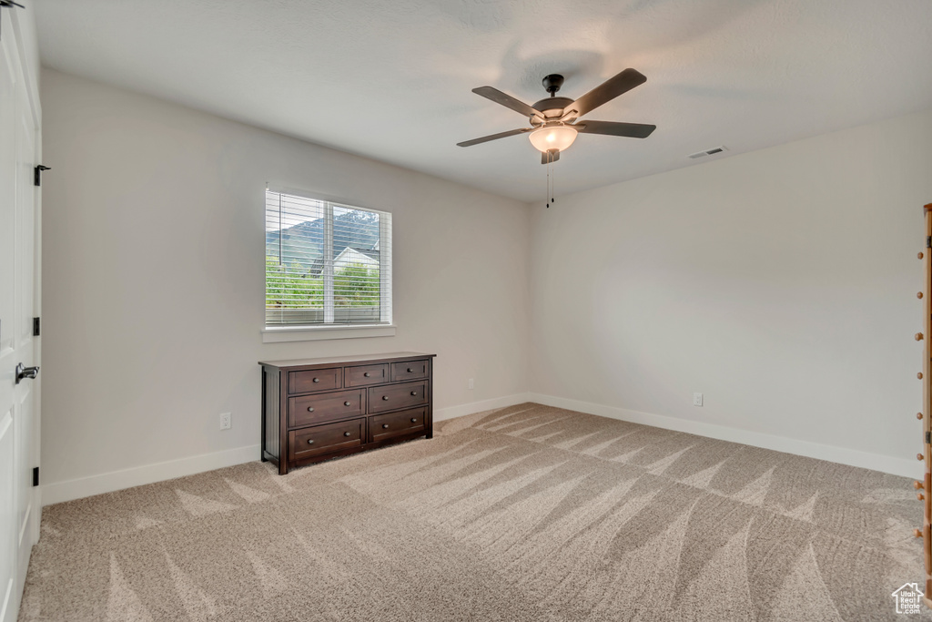 Spare room with ceiling fan, light carpet, and baseboards