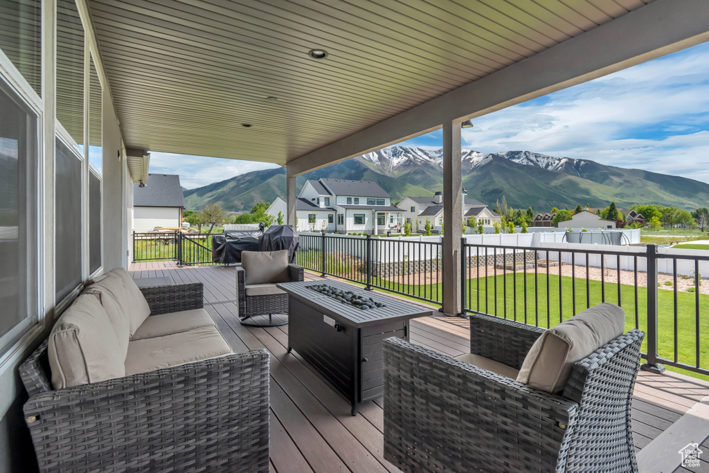 Wooden terrace with a mountain view, an outdoor living space with a fire pit, a lawn, and a residential view
