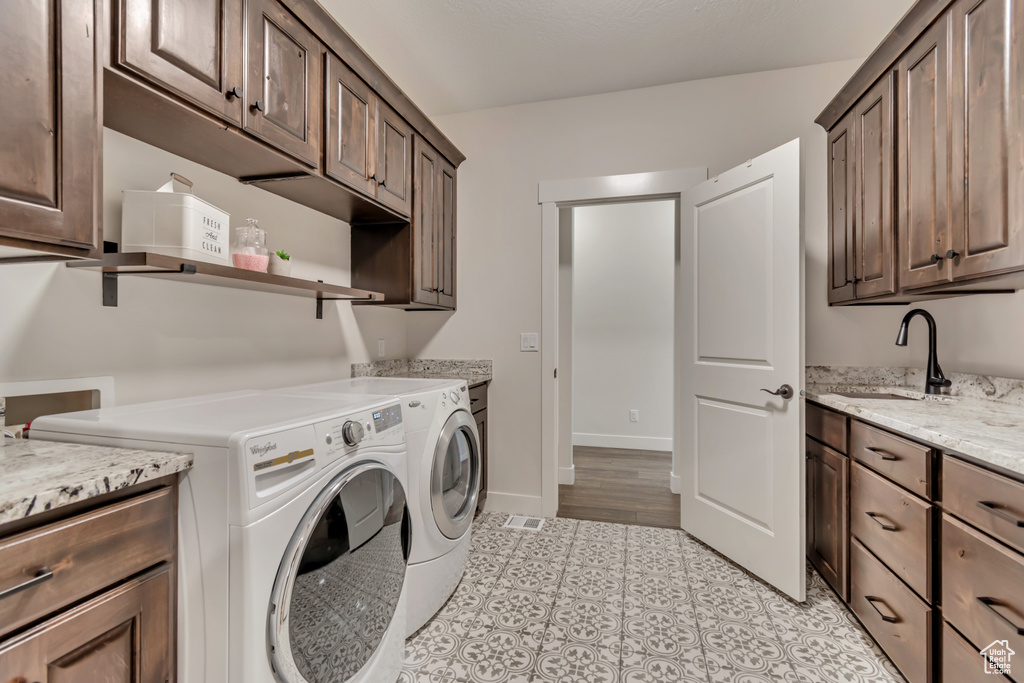 Washroom with cabinet space, washing machine and clothes dryer, light tile patterned flooring, and baseboards