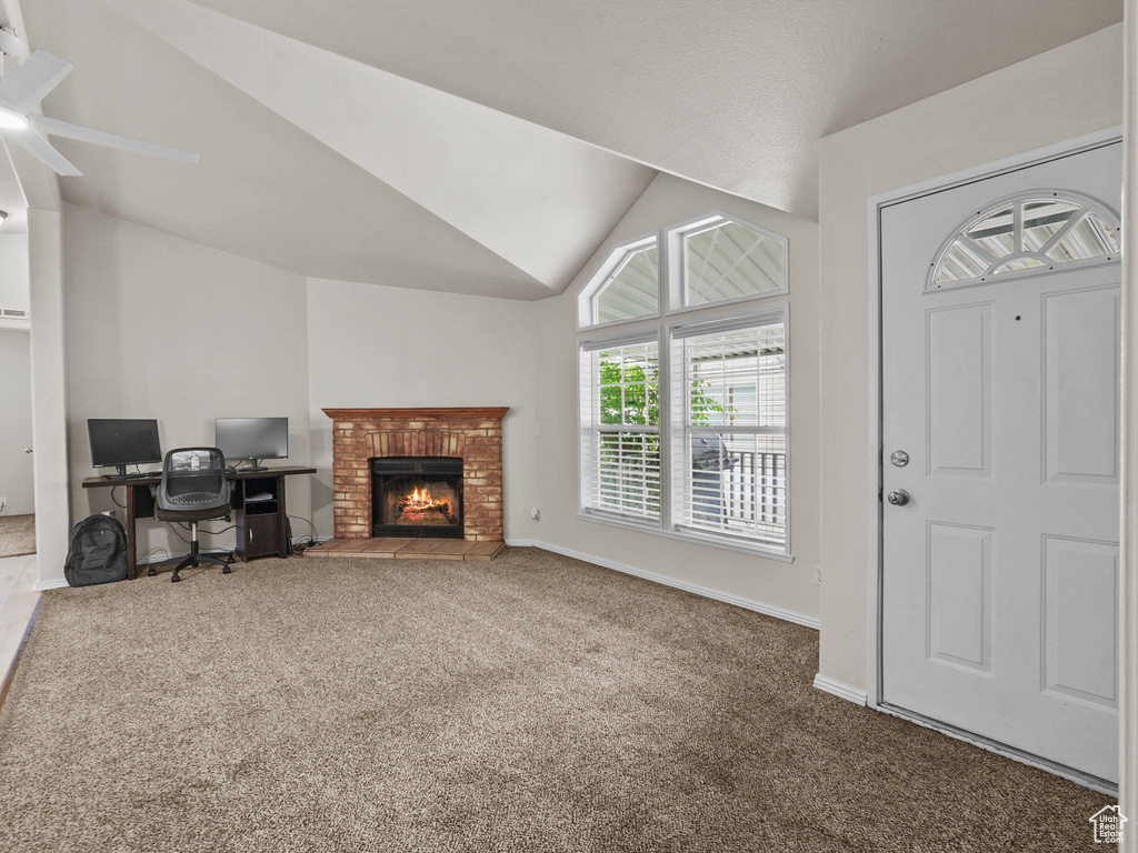 Living area featuring ceiling fan, carpet floors, lofted ceiling, a fireplace, and baseboards
