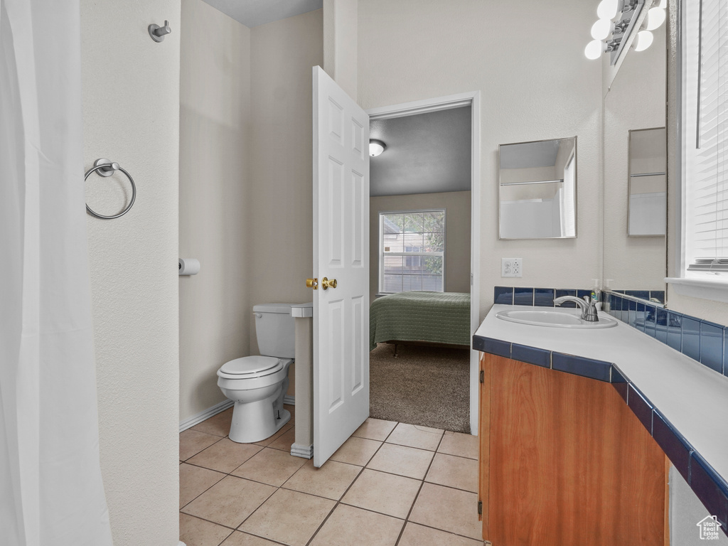 Bathroom with toilet, tile patterned flooring, vanity, and connected bathroom