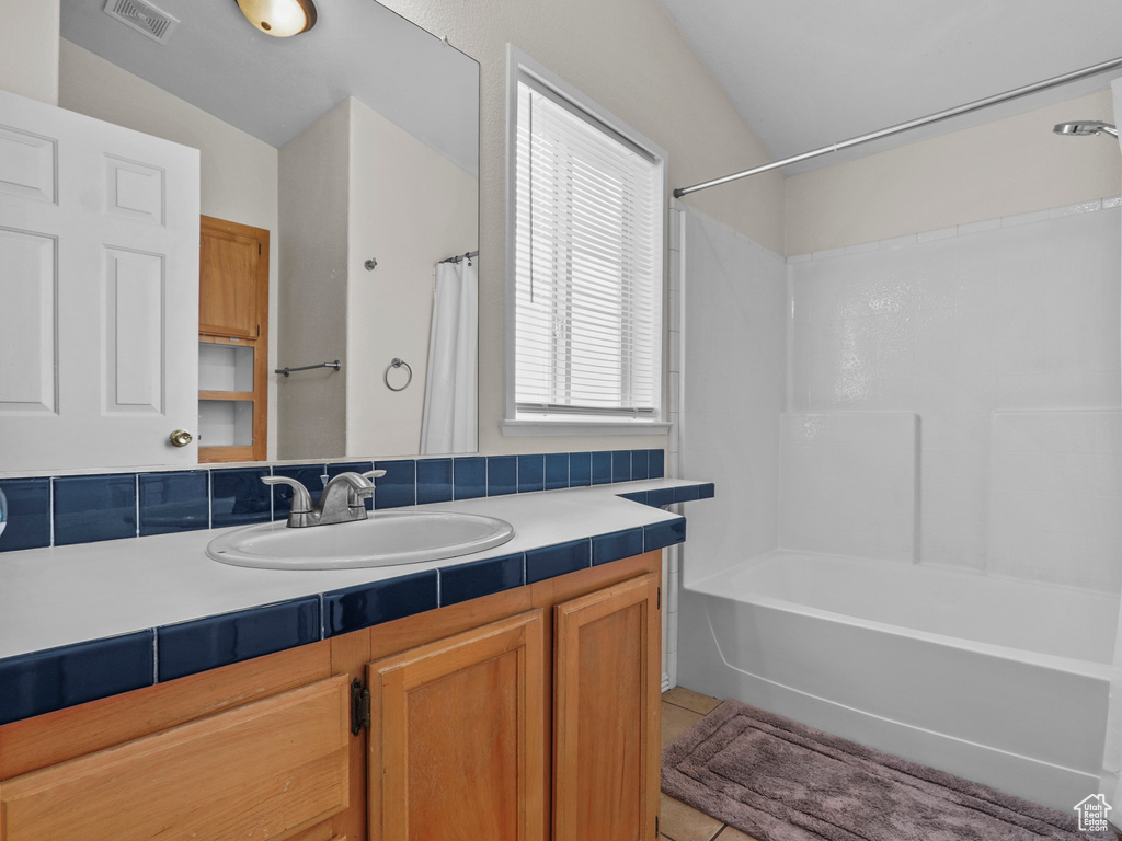 Bathroom featuring tile patterned floors, vanity, shower / bathtub combination, and vaulted ceiling