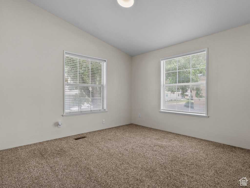 Carpeted spare room featuring lofted ceiling