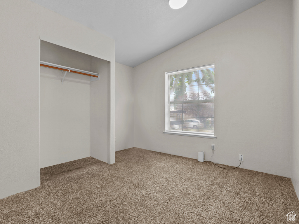 Unfurnished bedroom with carpet floors, vaulted ceiling, and a closet