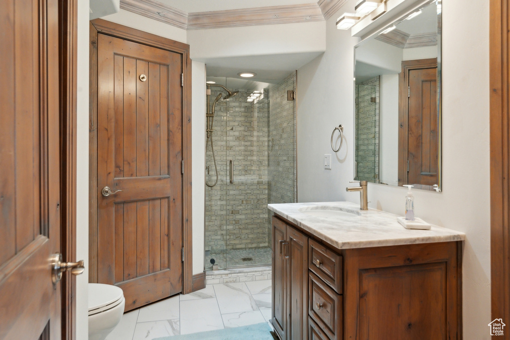 Bathroom featuring a shower stall, toilet, marble finish floors, vanity, and ornamental molding