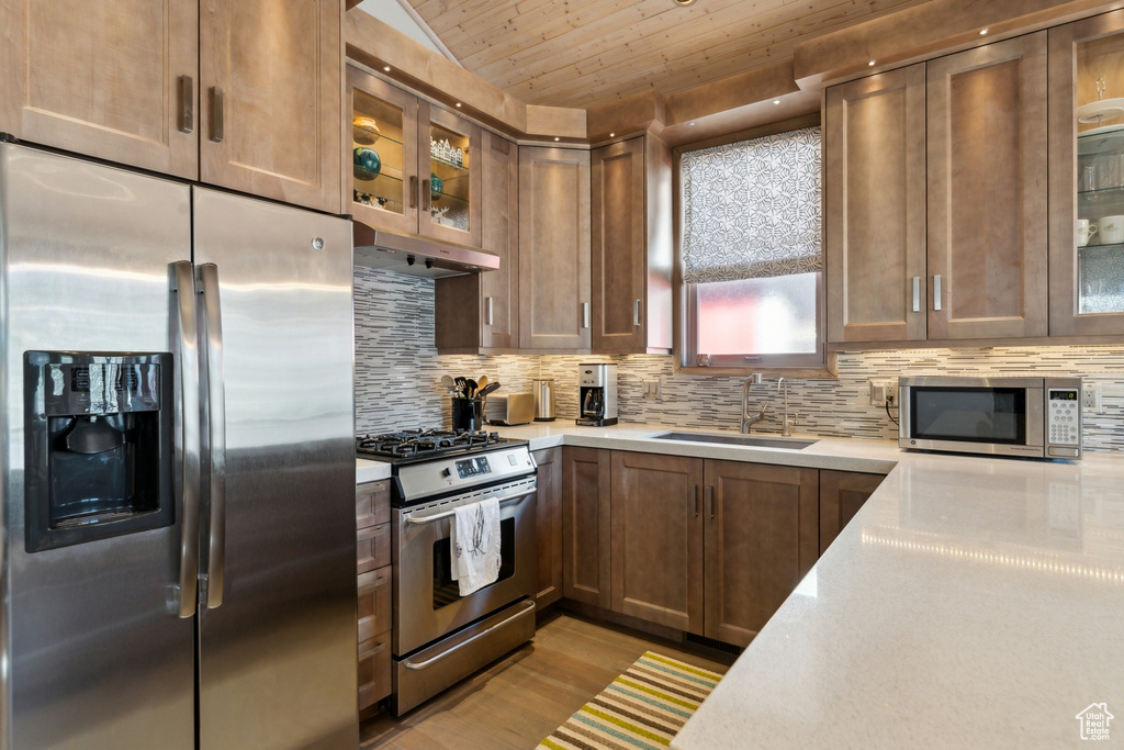 Kitchen featuring appliances with stainless steel finishes, a sink, light countertops, light wood-style flooring, and wooden ceiling